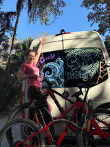 Adventure-ready rv rental with custom window art & mountain bikes, featuring a smiling woman.