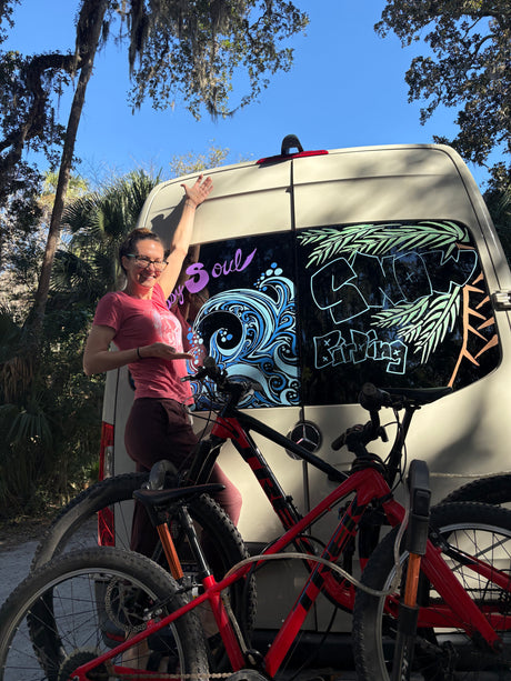Adventure-ready rv rental with custom window art & mountain bikes, featuring a smiling woman.