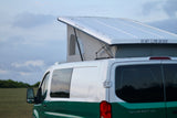 A green and white pop-top camper van, an RV rental, sits in a field under clouds. A sign warns: 'DO NOT CLIMB ON ROOF'.