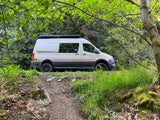 Camper van RV rental ready for adventure, parked in a lush forest. Ideal for outdoor exploration.