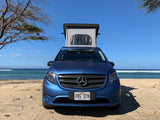 Blue Mercedes camper van RV rental on Hawaii beach with pop-top roof up, ocean backdrop.