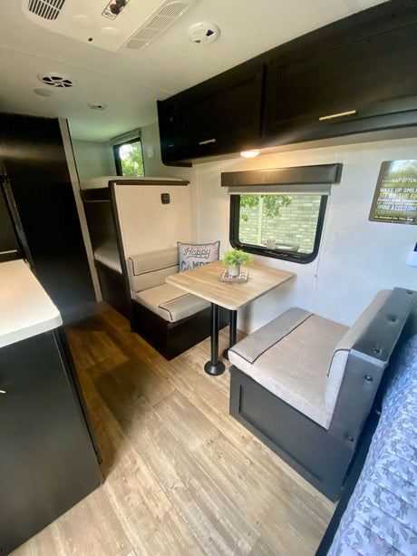 Step inside this RV rental's inviting interior: a bright dinette with a window, compact kitchen, and bunk beds in the rear.