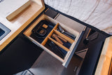 RV rental: An open, organized wooden drawer with black felt lining, holding kitchen utensils and tech, showcasing clever compact storage.