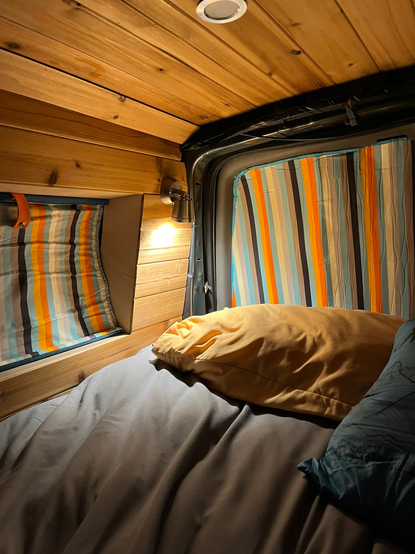 Cozy camper van RV rental interior. Wooden walls, striped curtains, warm light illuminate the bed. Road trip ready! — photo 8