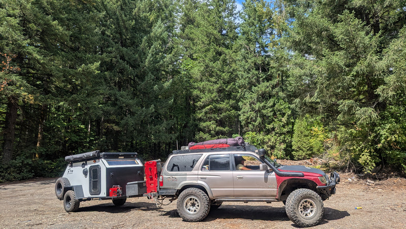 Off-road SUV towing an overland camping trailer through a dense forest. A rugged RV rental option for adventure travel. — photo 13