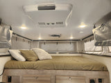 Inside an RV rental: a comfortable bedroom with a made bed, AC, ceiling fan, and soft-sided sleeping area.