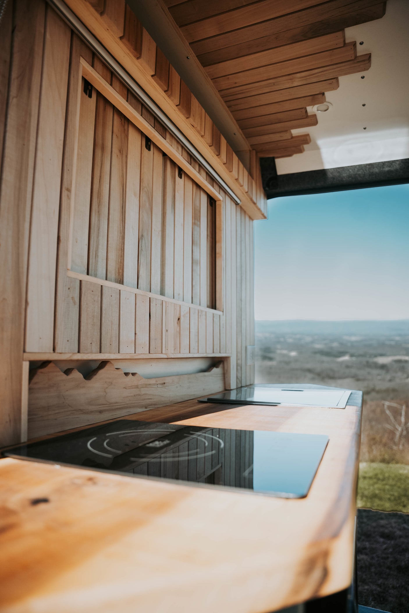 This inviting RV rental features a cozy wood-paneled kitchen with built-in cooktops and a vast mountain view.