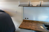 RV rental kitchen and bedroom amenities: wood counter, hex tile, USB charge points, and bed.