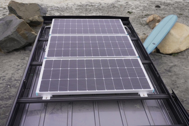 RV rental with three rooftop solar panels for off-grid beach adventures. Surfboard visible. — photo 6