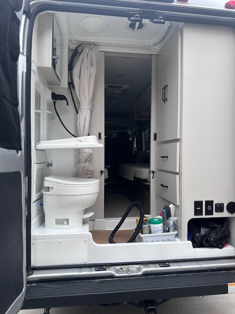 This compact RV rental interior features a clever wet bath with toilet & sink, plus integrated storage for mobile living convenience.