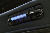 Luxury RV rental interior: black padded panel, with a chrome grab handle illuminated by a vibrant blue LED light.