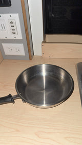 Stainless steel pan on a light wood counter in an RV rental kitchen, featuring USB and power outlets.