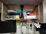 Organized RV rental kitchen cabinet with dishes, spices, and sink, showing practical storage solutions for travel.