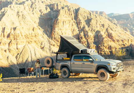 Woman by her overlanding Toyota Tacoma truck camper, a perfect RV rental for desert mountain adventures.
