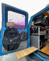 Inside an RV rental van: custom storage, tactical bags, and a handy fold-down table. Efficient space for travel.