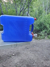 Blue portable water container, essential for RV rental adventures, sits by a stream in a lush forest.