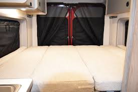 Explore an RV rental's versatile interior: a comfortable three-section bed ready for adventure, with screened rear doors.
