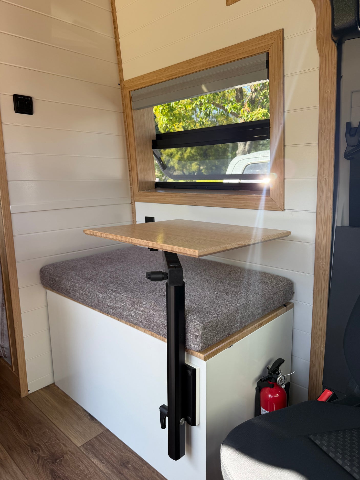 Cozy RV rental interior with a versatile table, comfortable bench seating, window view, and a readily accessible fire extinguisher.