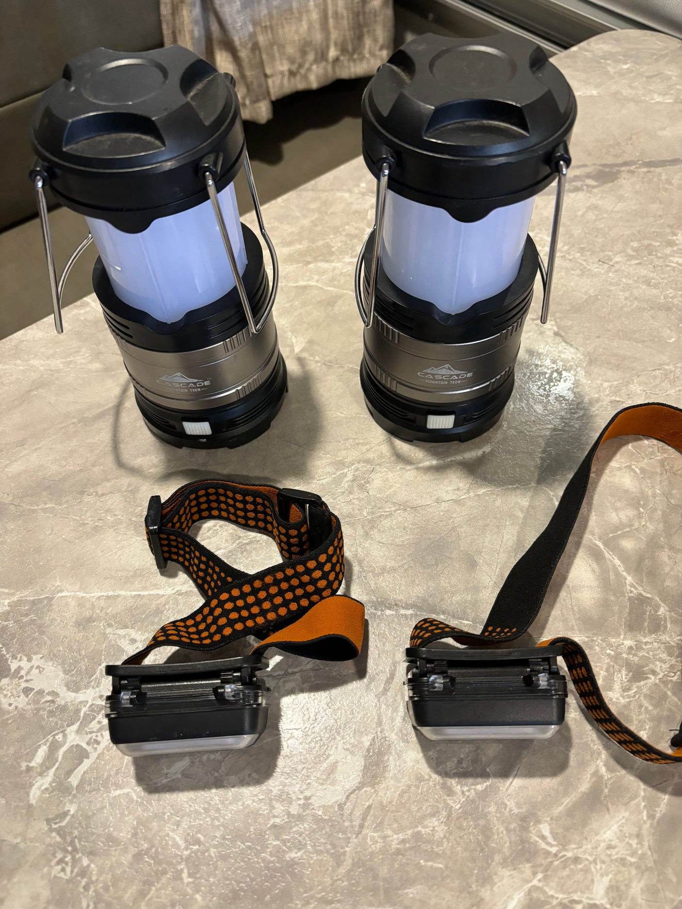 Essential gear for your RV rental adventure: two compact lanterns and two headlamps on a textured surface.
