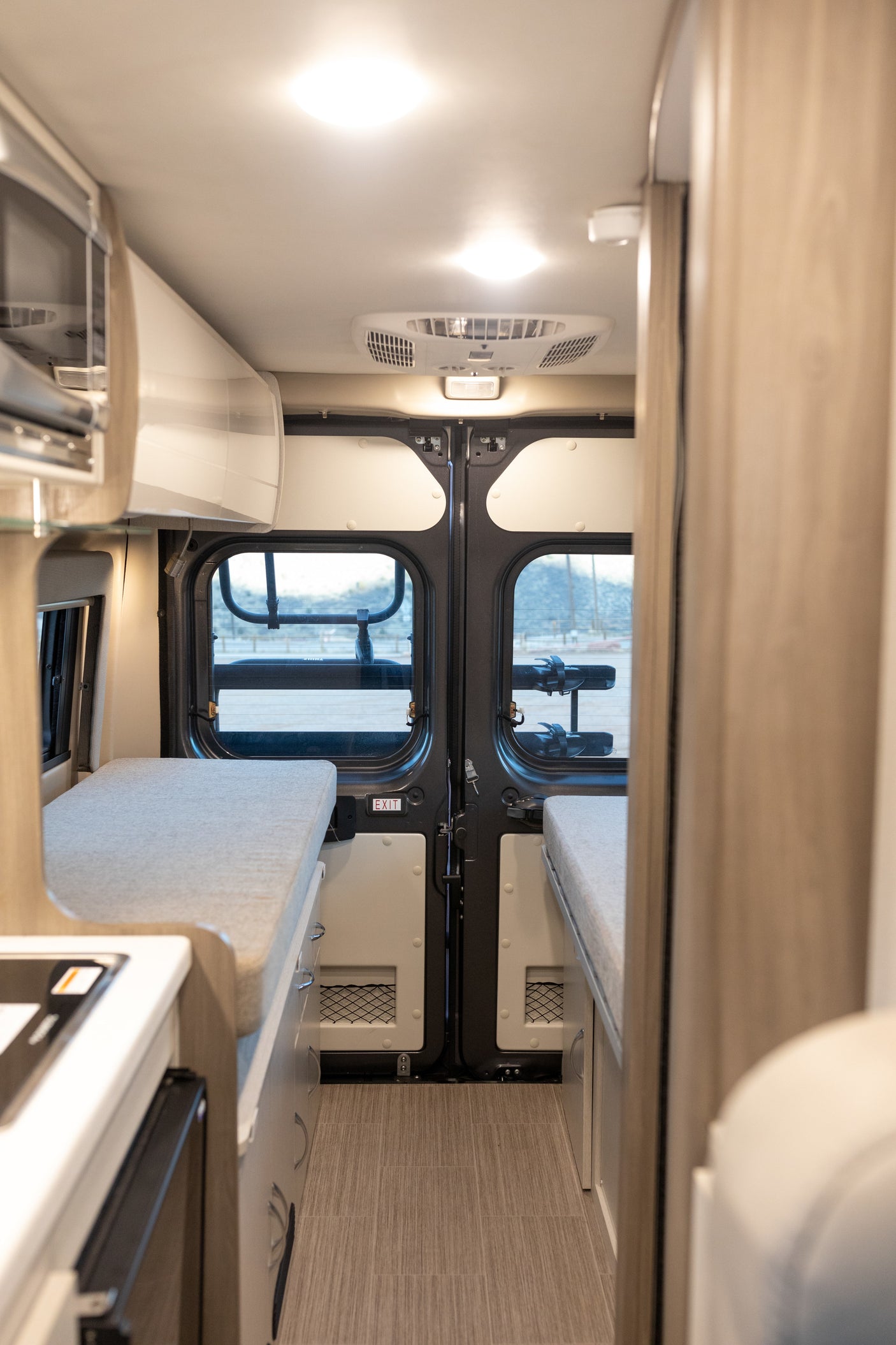 Step inside this modern RV rental. Features a compact kitchen, convertible bench beds, and rear exit doors.