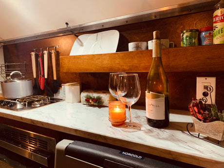 Cozy kitchen setup in an RV rental, complete with a two-burner stove, wine glasses, and festive holiday decor.