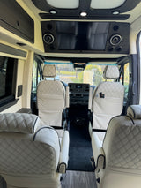 Luxurious RV rental interior, showing cream diamond-quilted seats, front dashboard, and entertainment system.