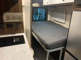 RV rental interior: cozy bed, compact kitchen with induction cooktop, and smart storage for road adventures.
