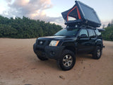 This black Nissan Xterra, an RV-style rental, with a deployed rooftop tent for off-road camping on sand.