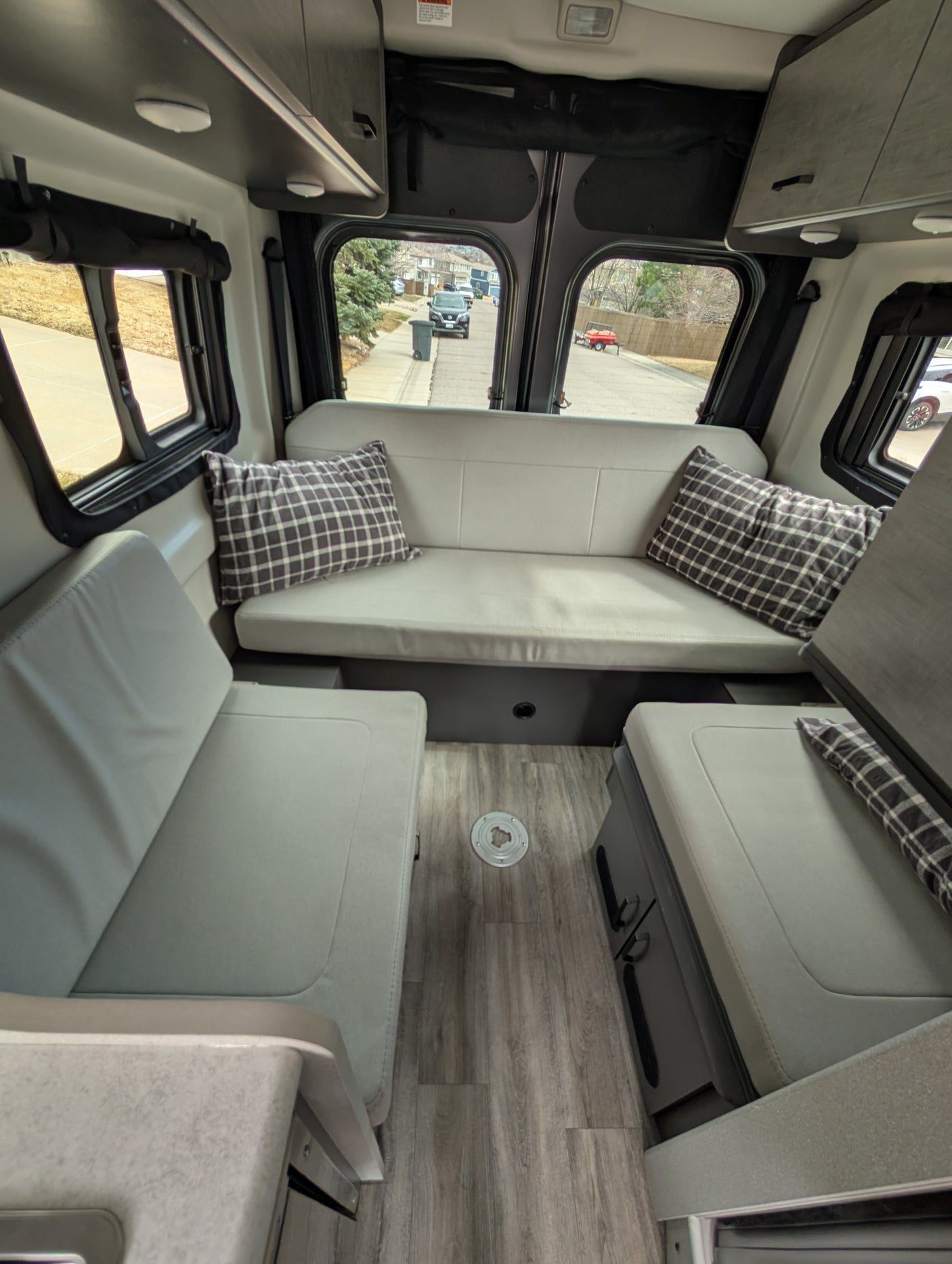 Comfortable RV rental interior with cozy seating, wood floor, and overhead storage, perfect for road trips.