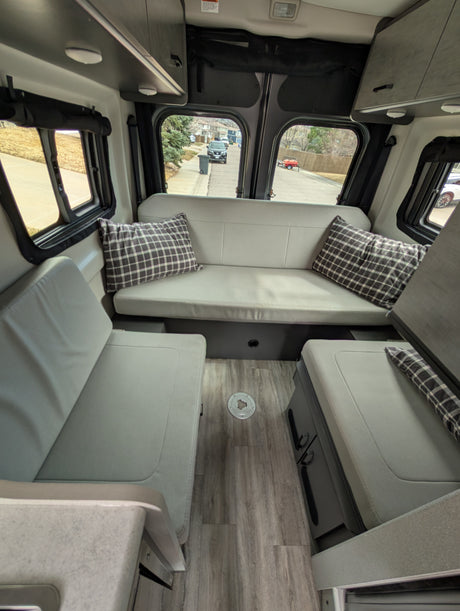 Comfortable RV rental interior with cozy seating, wood floor, and overhead storage, perfect for road trips.
