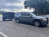 A gray SUV tows a black utility trailer. Perfect for hauling gear, complementing an rv rental adventure.