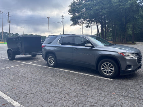 A gray SUV tows a black utility trailer. Perfect for hauling gear, complementing an rv rental adventure.