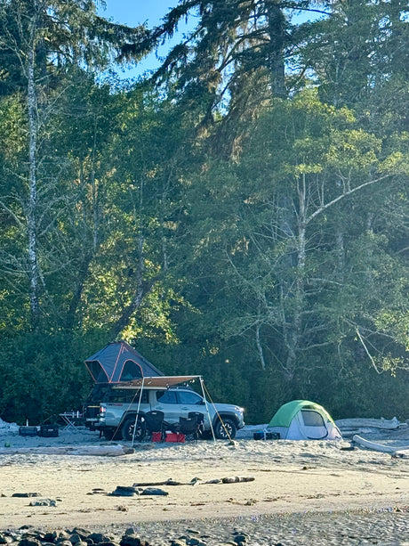Beach camping with a truck & rooftop tent next to a ground tent. A versatile RV rental alternative for outdoor adventures by the forest.