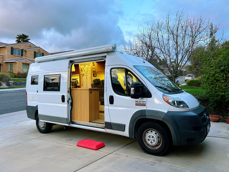 White Ram ProMaster **rv rental** van conversion with lit interior and extended awning — photo 1