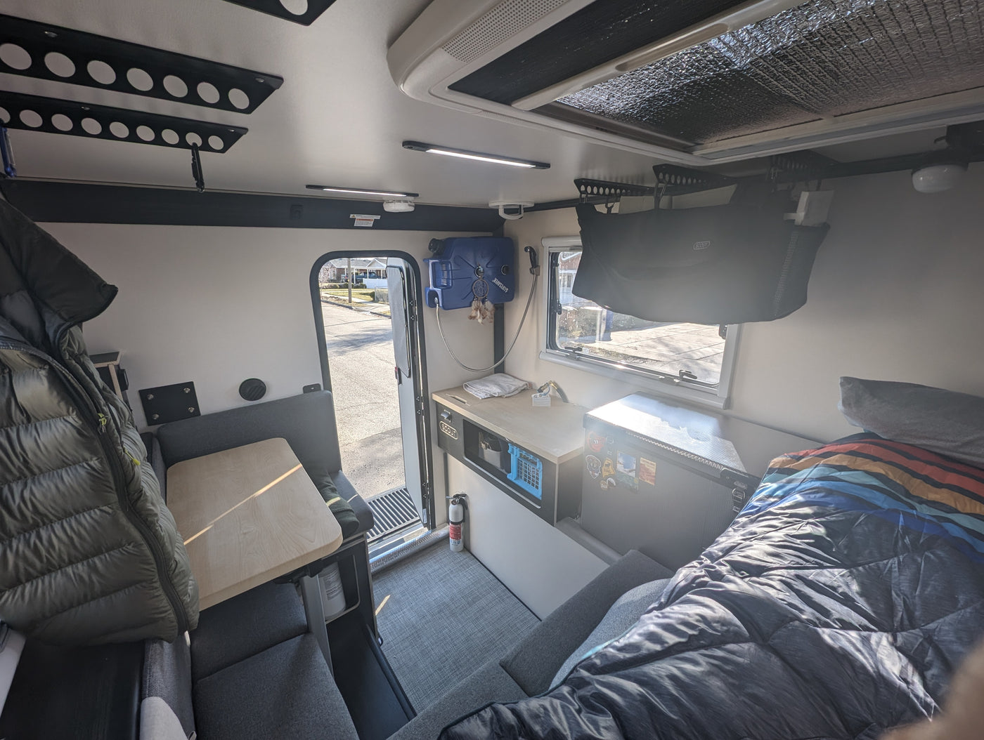 Cozy RV rental interior showcasing a dinette, functional kitchen, and comfortable sleeping area. Perfect for adventure. — photo 7