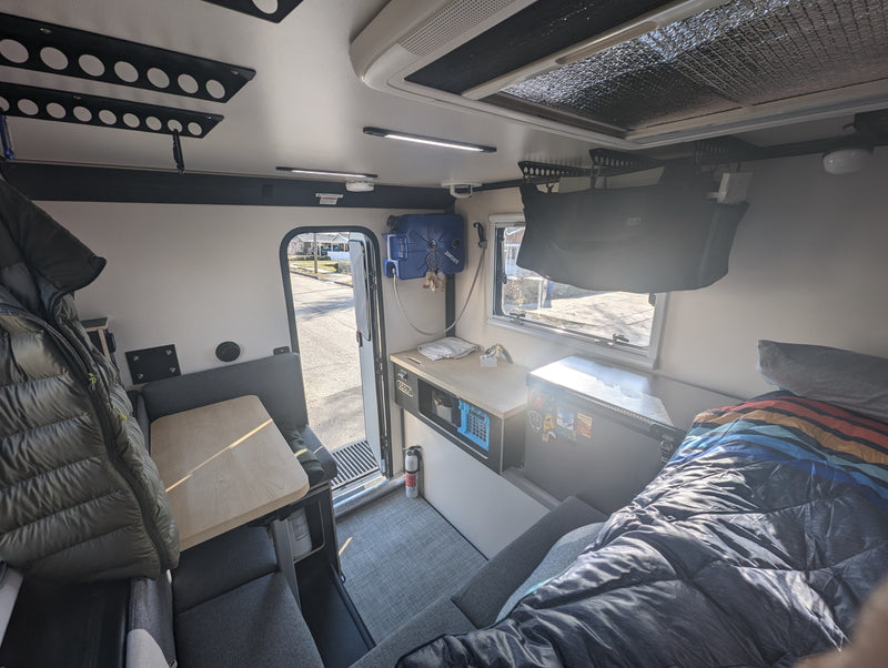 Cozy RV rental interior showcasing a dinette, functional kitchen, and comfortable sleeping area. Perfect for adventure. — photo 7