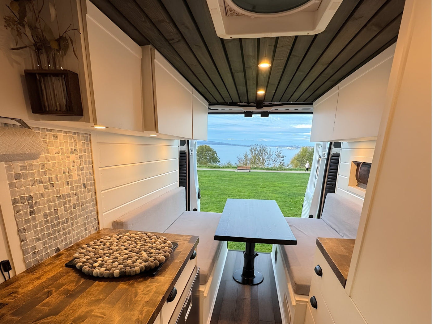  and a scenic water view. Ideal for road trips.|This RV rental offers a charming camper van interior with a comfortable dining space — photo 5