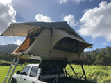 An RV rental alternative: a truck with a rooftop tent set up in a scenic mountain landscape under blue skies.