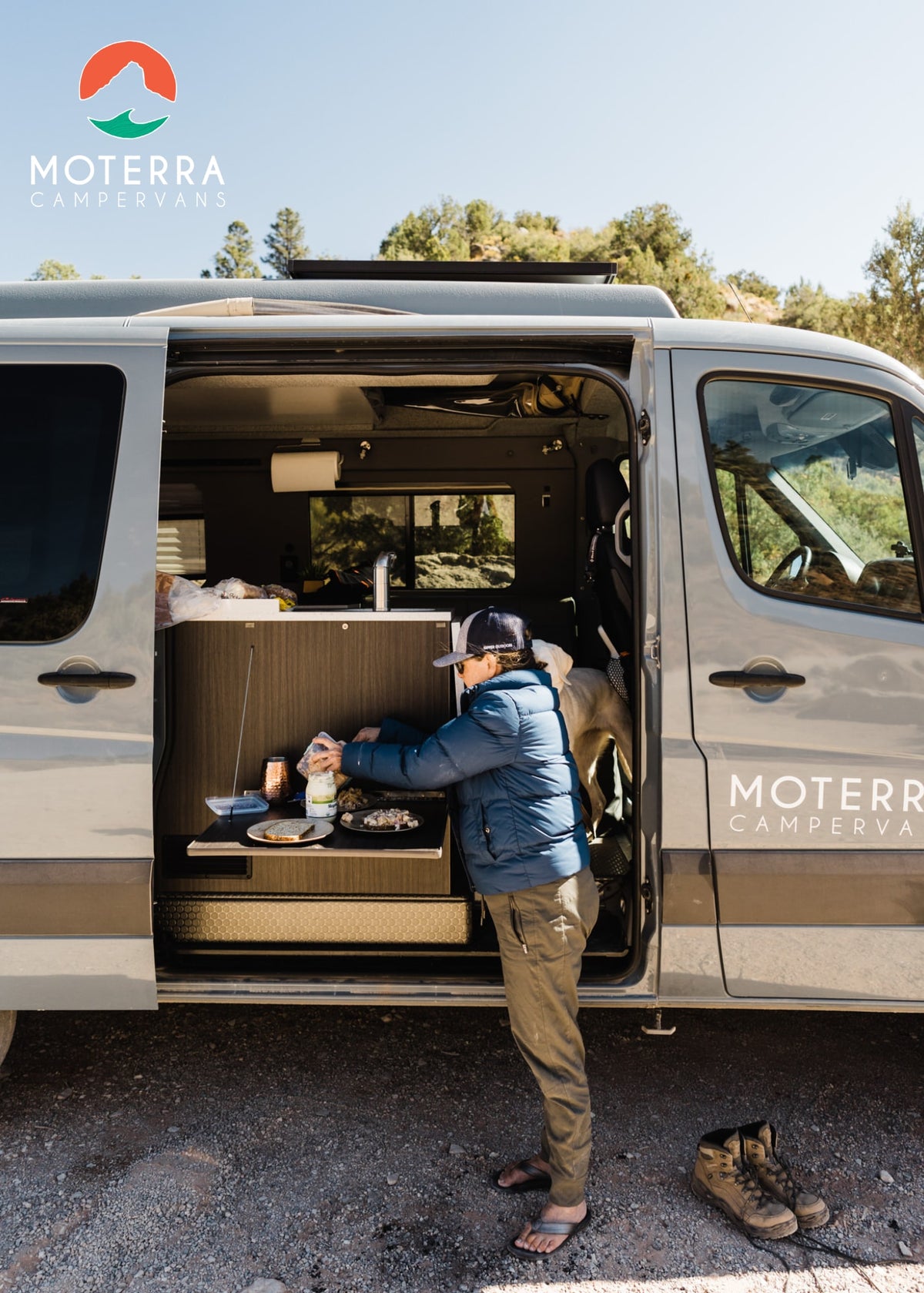 An adventurer cooks outside their grey Moterra RV rental campervan