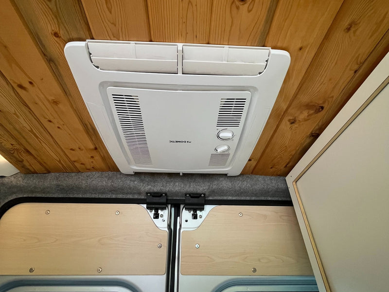  and light wood countertop by a window.|Spacious camper van rv rental interior with wooden ceiling — photo 18