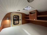 Inside a cozy rv rental: a light-filled bedroom with a textured mattress, wooden walls, built-in storage, and a ceiling fan.