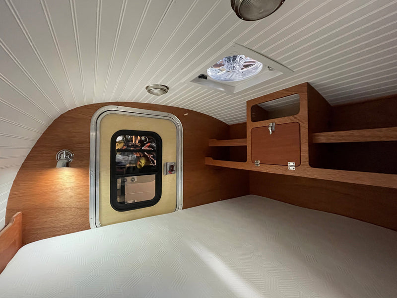 Inside a cozy rv rental: a light-filled bedroom with a textured mattress, wooden walls, built-in storage, and a ceiling fan. — photo 19