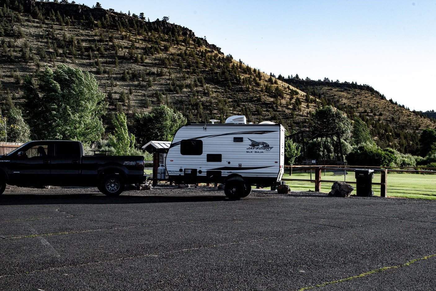 This RV rental and truck are parked, ready for outdoor adventures in a scenic, tree-filled landscape.