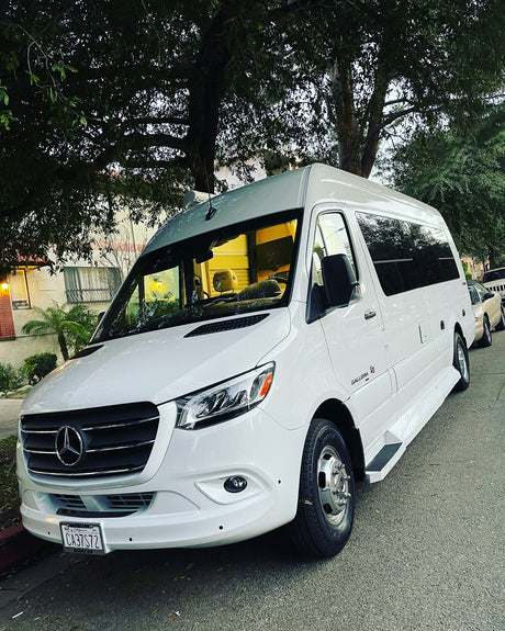 White Mercedes-Benz Sprinter RV rental, a sleek camper van parked on a residential street lined with trees.