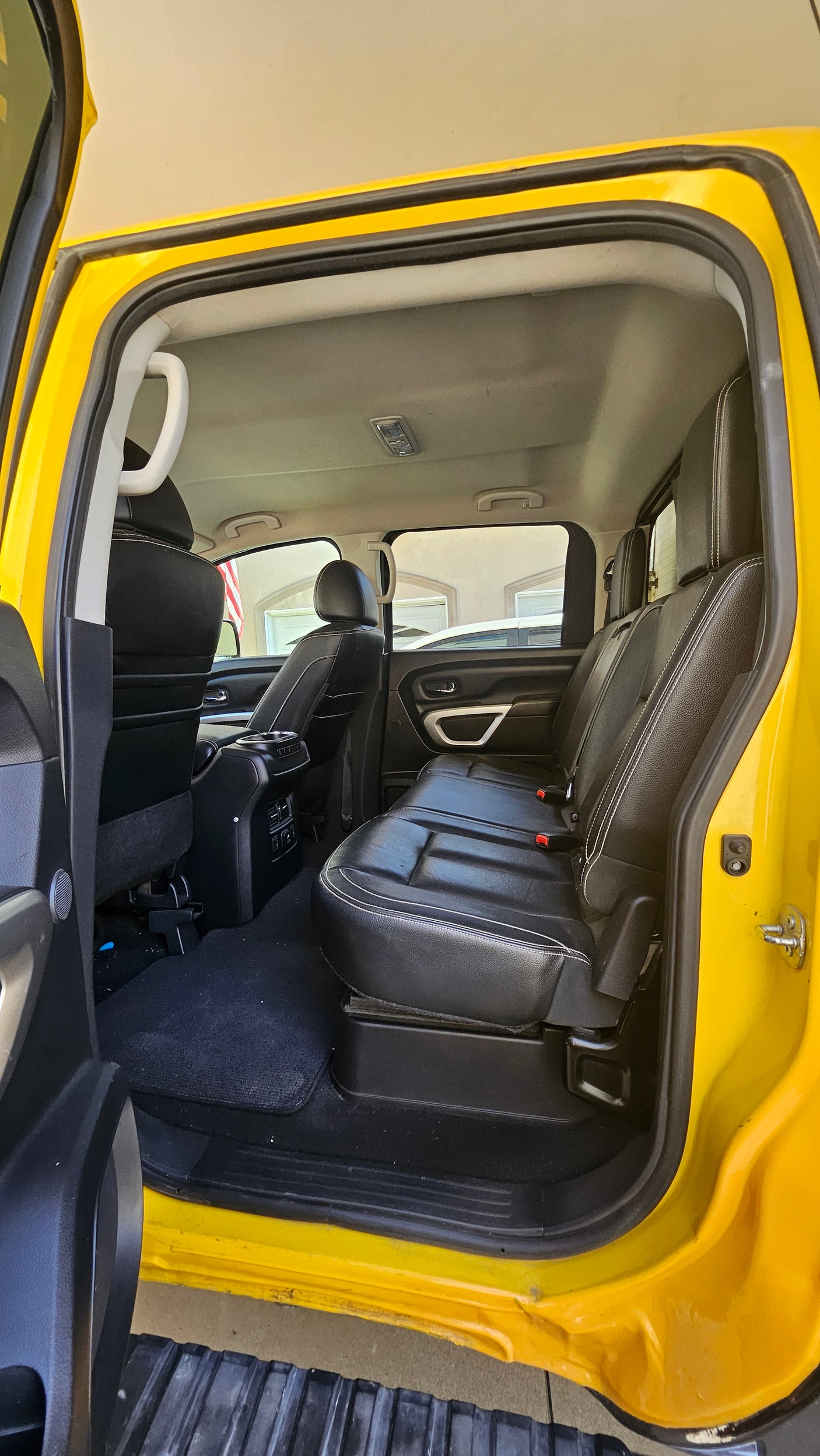Spacious yellow RV rental interior: view of the rear cabin with black leather seats, console, and grab handles.