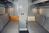 Modern RV rental interior: cozy facing benches with pillows, reading lights, and central storage.