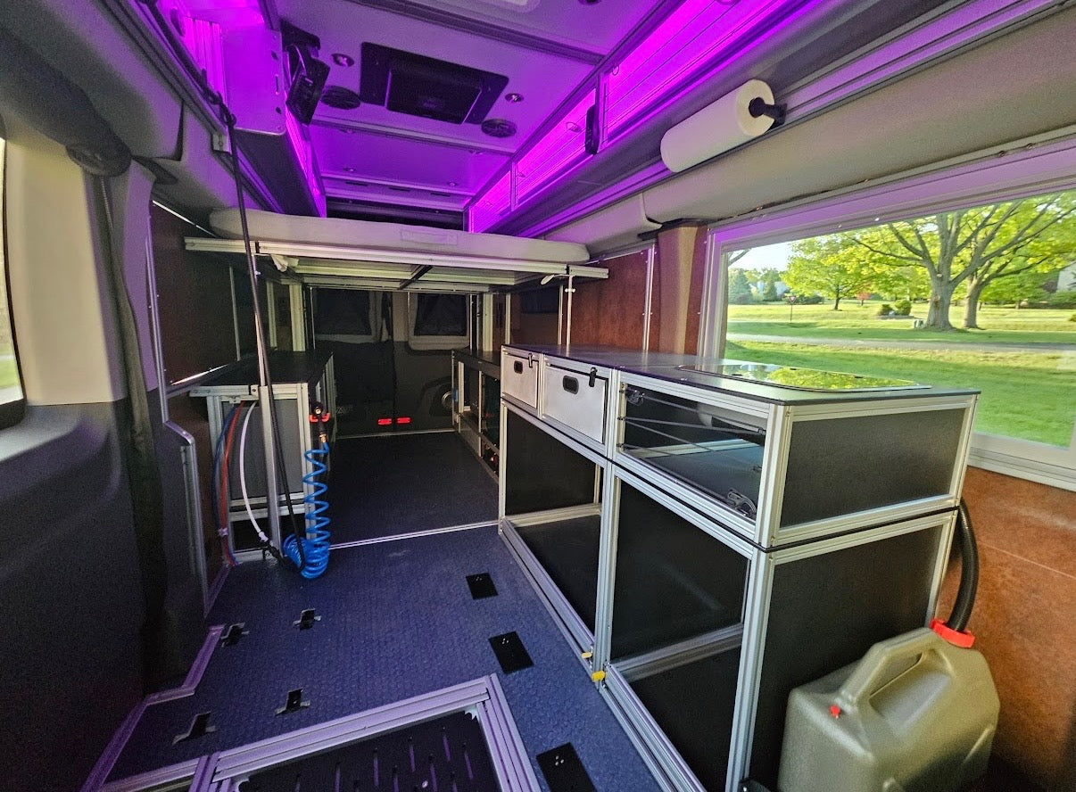 Interior of a customizable rv rental, a modular van conversion with bed, cabinets, and ambient purple lighting.