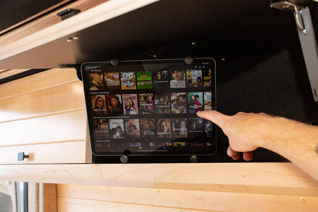 Mounted tablet displaying Netflix in an RV rental, providing on-the-go entertainment as a hand interacts with it.