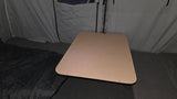 Interior of an RV rental: a light wood table and sleeping area within a pop-up camper's grey fabric walls.