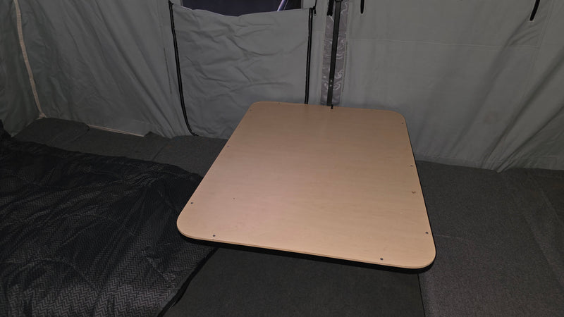 Interior of an RV rental: a light wood table and sleeping area within a pop-up camper's grey fabric walls. — photo 5